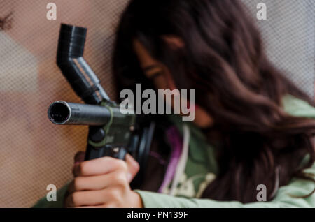 Little girl playing with a paintball gun shooting to the target Stock Photo