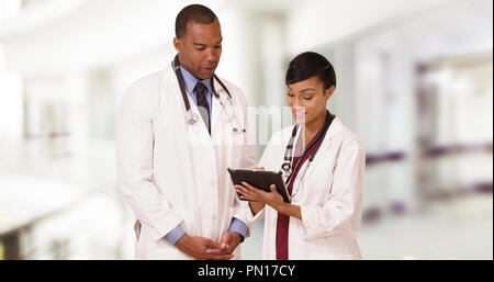 Two professional African American doctors talk while using their tablet Stock Photo