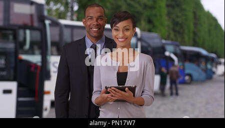 Two young African tour guides posing proudly near some tour buses Stock Photo