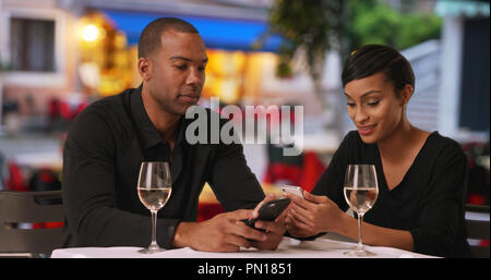 Black man and woman on a date checking social media on smartphones Stock Photo