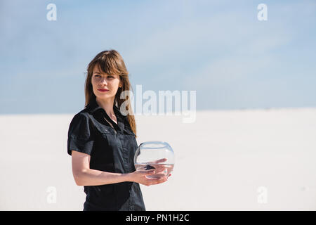 Woman with aquarium fish in the desert Stock Photo