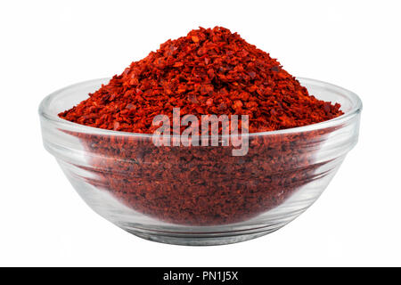 Dried red pepper, chilli flakes in a glass bowl, isolated on white background Stock Photo