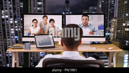 Businessman in office at night talking to international co workers Stock Photo