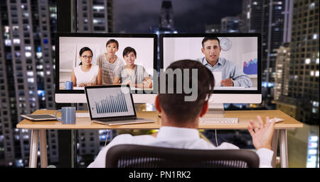 Businessman in office at night talking to international co workers Stock Photo