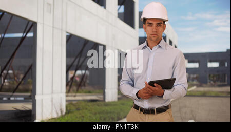 Young handsome architect at construction site holding modern tablet Stock Photo