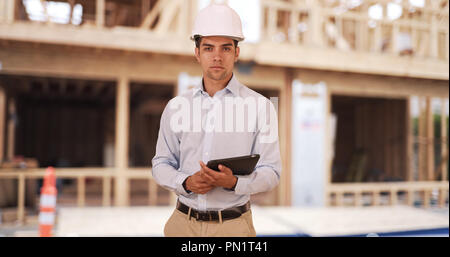 Millennial Hispanic architect on construction site wearing hard hat helmet Stock Photo