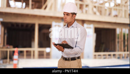 Millennial Latino architect contractor on construction site wearing hard hat Stock Photo