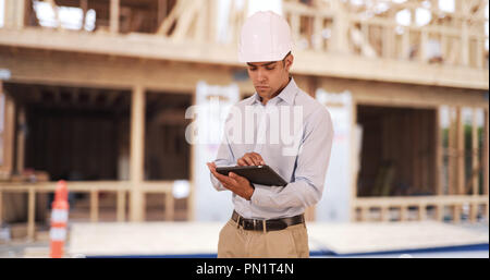 Millennial Latino architect contractor on construction site wearing hard hat Stock Photo