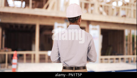 Rear view of Latino architect on construction site wearing hard hat helmet Stock Photo