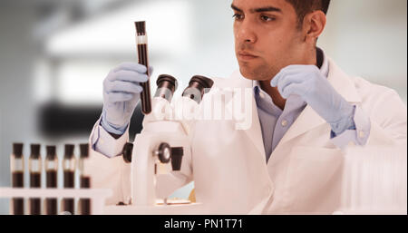 Millennial Hispanic medical scientist in laboratory looking through microscope Stock Photo