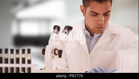 Millennial Hispanic medical scientist in laboratory looking through microscope Stock Photo