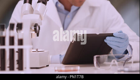 Close up of male medical scientist swiping and typing on touchscreen device Stock Photo