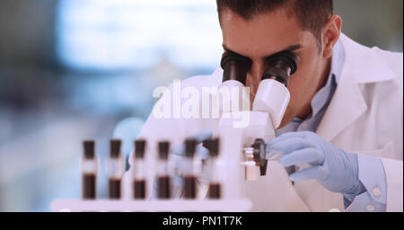Hispanic male forensic scientist examining blood sample in lab Stock Photo