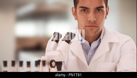Portrait of Millennial Hispanic medical research scientist in lab using microscope Stock Photo