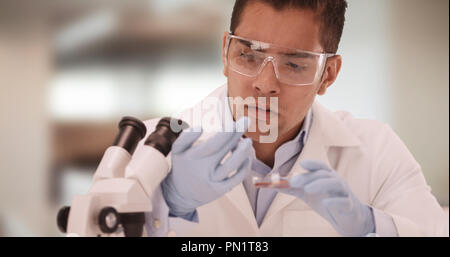 Millennial Latino medical research or food scientist eats out of petri dish Stock Photo