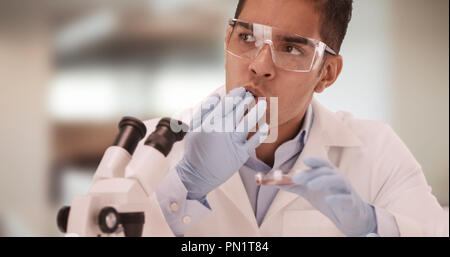 Millennial Latino medical research or food scientist eats out of petri dish Stock Photo