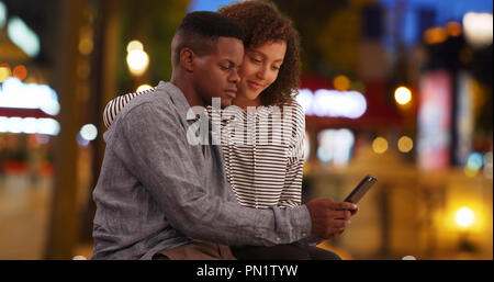 Cute African American couple relax on Champs-Elysees avenue using smartphone Stock Photo