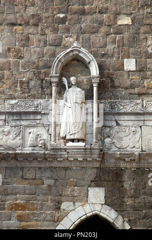 Statue (14th century) of San Giusto decorates the entrance to the  bell tower of the Cathedral of San Giusto in Trieste, Italy.  He is holding a palm  Stock Photo