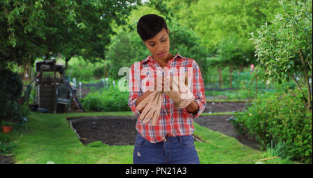 Healthy young black woman in her garden removing gloves exhausted Stock Photo