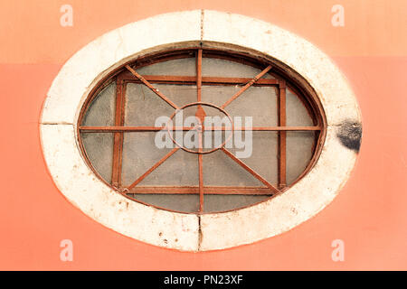 Round window with iron bars. Old ancient metal window. Round and arched window with wrought iron bars in a classic style. Stock Photo
