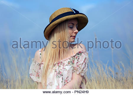 Blonde woman in a summer dress sitting in the long grass Stock Photo