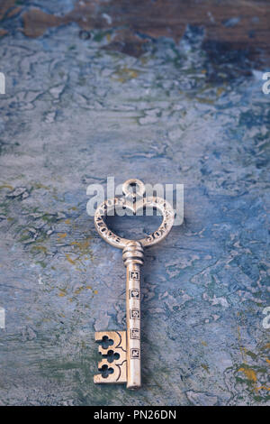 Old key isolated on concrete background with symbols of love, joy, friendship, luck, toned Stock Photo