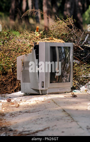 Discard old TV sets on a street, television near the container thrown, the natural environment. A TV thrown out with garbage. Throwing out garbage. Stock Photo