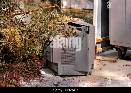 Discard old TV sets on a street, television near the container thrown, the natural environment. A TV thrown out with the garbage. Throwing out garbage Stock Photo