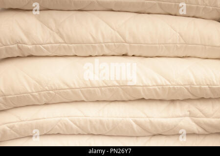 Stack of warm plaid and pillows on white shelf against striped wall background. Stock Photo