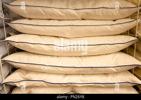 Stack of warm plaid and pillows on white shelf against striped wall background. Stock Photo