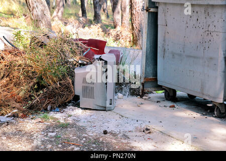 Discard old TV sets on a street, television near the garbage container thrown, natural environment. A TV thrown out with the garbage. Throwing out. Stock Photo