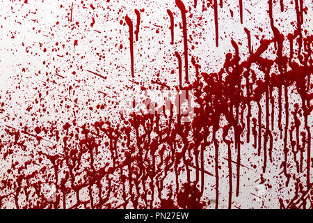 Old weathered concrete wall against of metal mesh with spots and stains of red paint similar to blood. Stains of red paint on the wall. Stock Photo