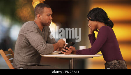 Couple drinking coffee and browsing internet on smartphones on date Stock Photo