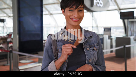 Spunky African woman at airport poses confidently with passport Stock Photo