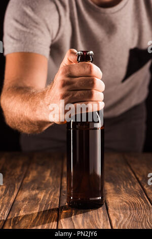 cropped image of man opening beer bottle at wooden table Stock Photo