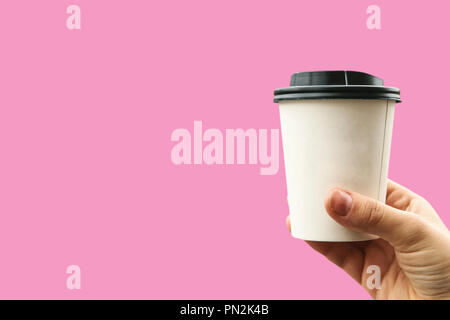 The girl holds a disposable glass in her hand with coffee or another drink on a pink background. Nearby place for text. Stock Photo