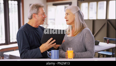 Elderly caucasian couple looking at tablet computer during breakfast Stock Photo