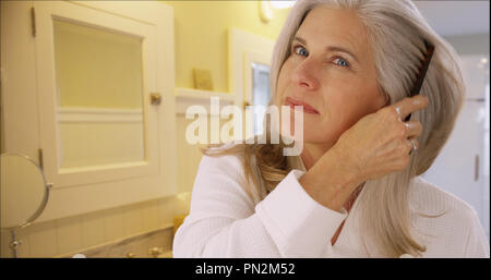 Closeup portrait of a mid aged woman combing her hair Stock Photo