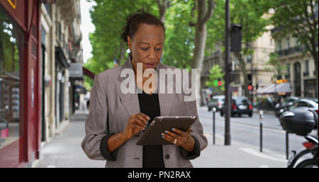 Mature businesswoman uses wireless tablet on urban street Stock Photo