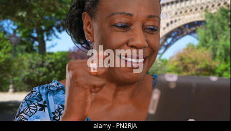 Elderly black woman near Eiffel Tower uses digital tablet Stock Photo