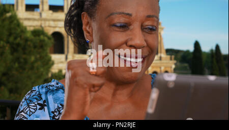Happy mature black woman using digital tablet near the Coliseum Stock Photo