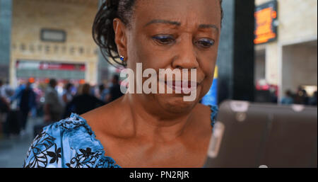 Older African American woman waiting at the airport uses digital tablet Stock Photo