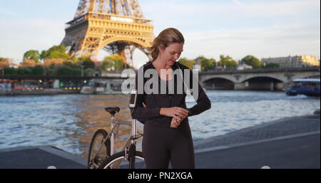 Sportive woman with bike in Paris using a smartwatch Stock Photo