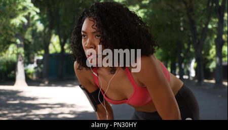 African American woman runner checking fitness tracker while jogging in the park Stock Photo