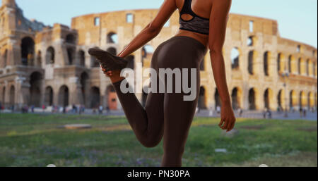 Close up of black woman athlete stretching in front of the Coliseum in Rome Stock Photo