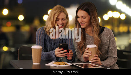 Couple of happy girls drinking using cellphone in Paris France Stock Photo