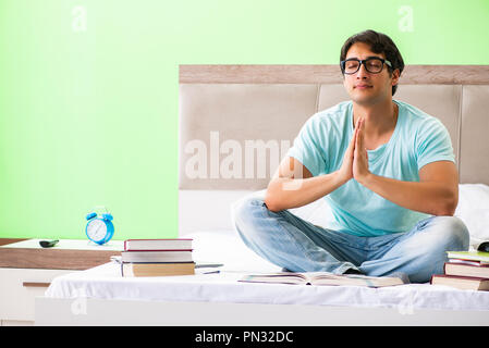 Student preparing for exams at home in bedroom sitting on the bed Stock Photo