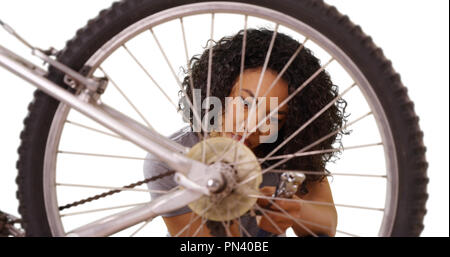 Young focused African lady on white copy space repairing bicycle alone Stock Photo