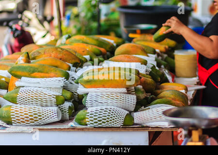 Extra jumbo size of ripe big yellow papaya fruit wrapped in protective net for sale at the fruit market in Bangkok, Thailand. Organic ripe papaya vend Stock Photo