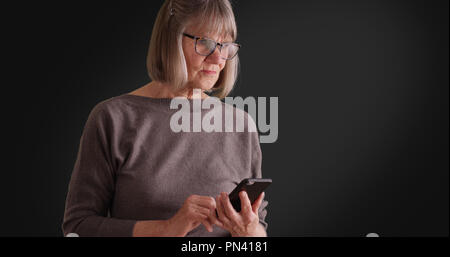 Somber lady reading worrying message on mobile device on dark gray background Stock Photo